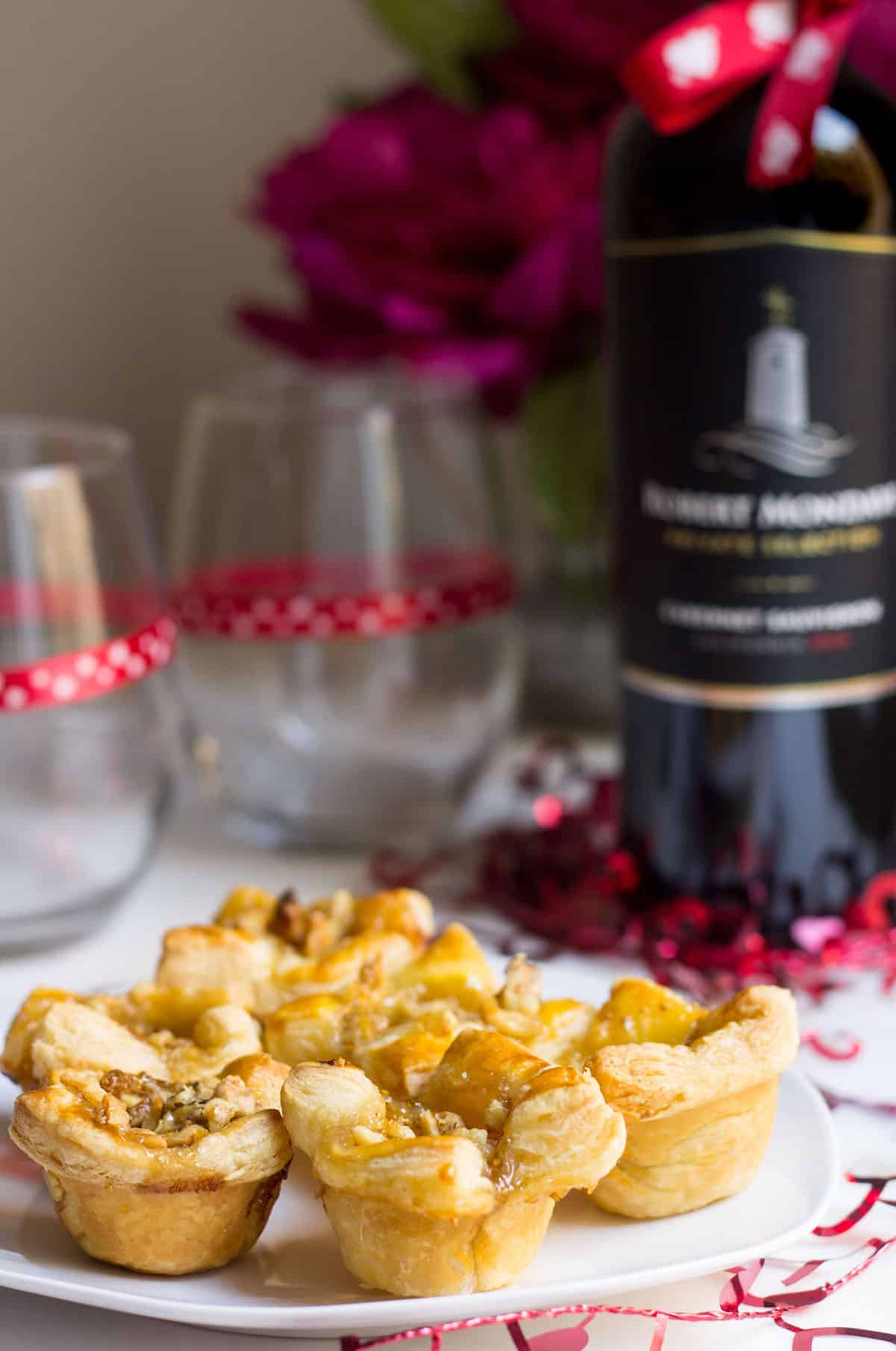 Fig Brie Bites perfect for entertaining! Creamy brie inside golden puff pastry, topped with sweet fig preserves and crunchy walnut pieces. Recipe via MonPetitFour.com