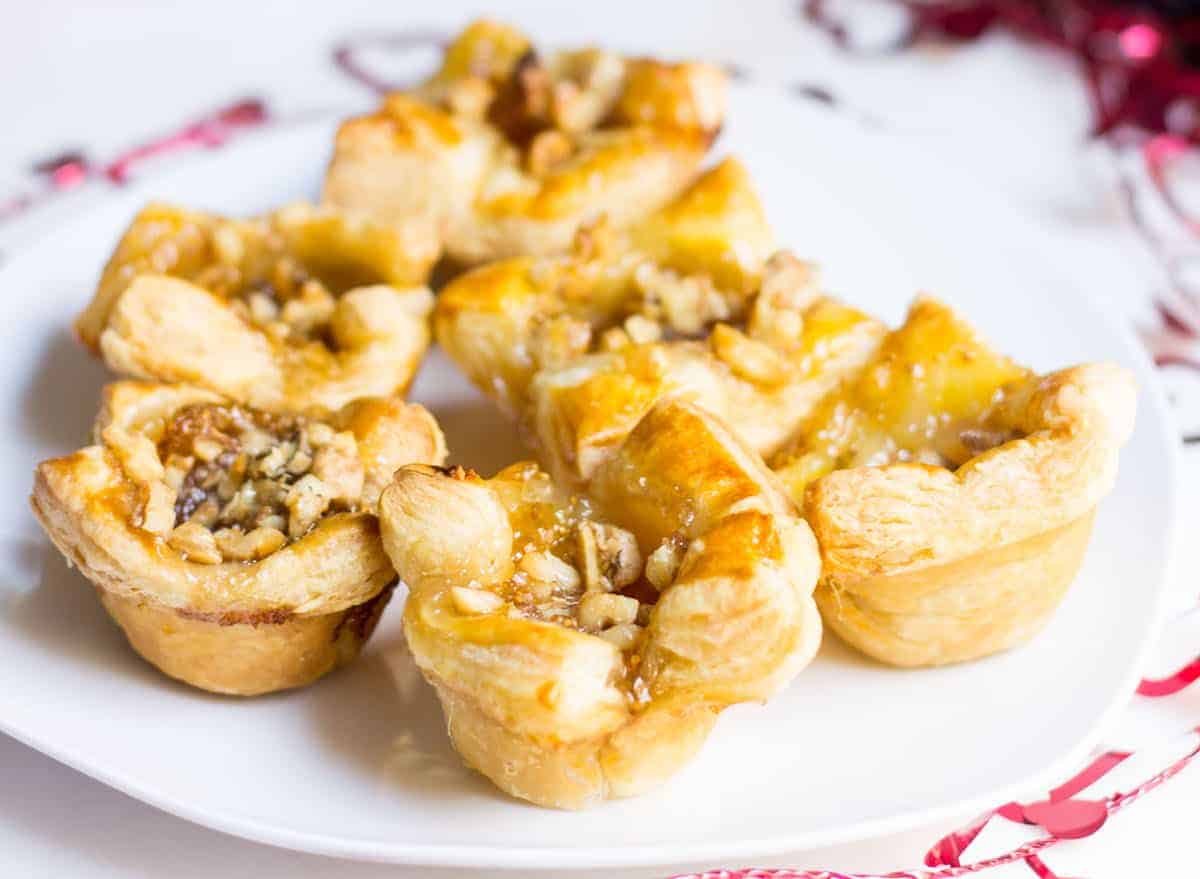 Fig Brie Bites perfect for entertaining! Creamy brie inside golden puff pastry, topped with sweet fig preserves and crunchy walnut pieces. Recipe via MonPetitFour.com