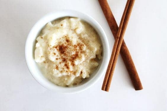 easy rice pudding in a ramekin next to cinnamon sticks