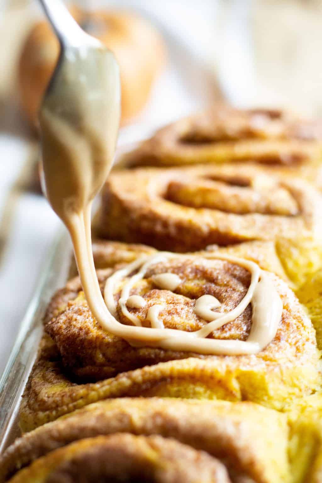 pumpkin cinnamon rolls icing falling off the spoon image