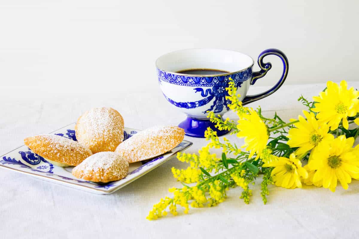Madeleines recipe on a plate next to a cup of coffee