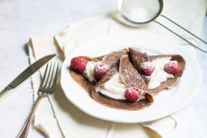 Chocolate Crepes filled with cream and fresh raspberries, then dusted with powdered sugar. So easy and so delicious! Recipe via MonPetitFour.com