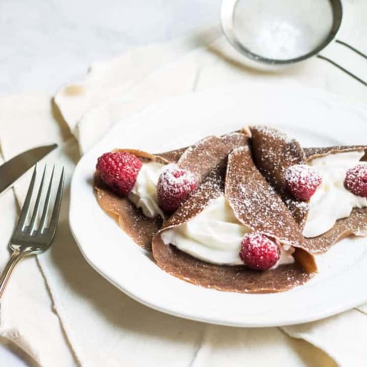Chocolate Crepes filled with cream and fresh raspberries, then dusted with powdered sugar. So easy and so delicious! Recipe via MonPetitFour.com