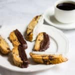 Chocolate-Dipped Almond Biscotti: a crisp almond cookie filled with dark chocolate, orange zest, and almonds. Perfect as a winter dessert, served with a cup of hot coffee. Recipe via MonPetitFour.com