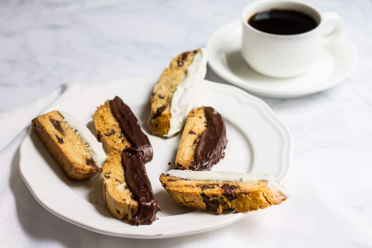 Chocolate-Dipped Almond Biscotti: a crisp almond cookie filled with dark chocolate, orange zest, and almonds. Perfect as a winter dessert, served with a cup of hot coffee. Recipe via MonPetitFour.com