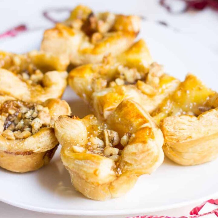 Fig Brie Bites perfect for entertaining! Creamy brie inside golden puff pastry, topped with sweet fig preserves and crunchy walnut pieces. Recipe via MonPetitFour.com