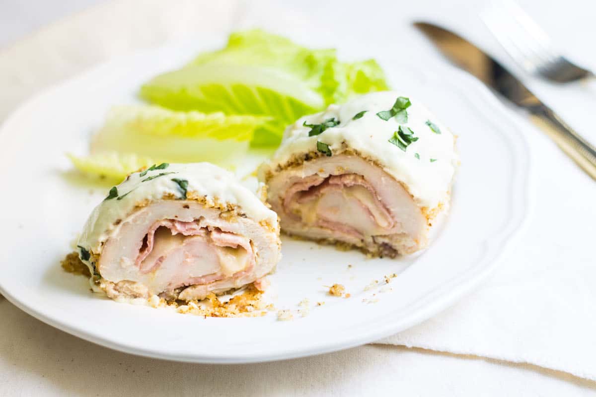 Chicken Cordon Bleu: an easy and quick French dinner! This classic is made with breaded chicken stuffed with ham and cheese. Topped with a dijon cream sauce. Recipe via MonPetitFour.com