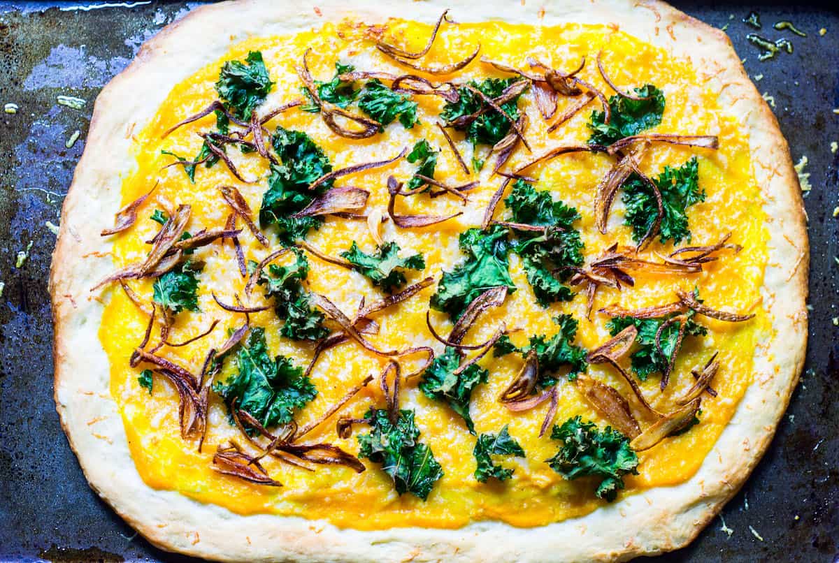 Butternut Squash Pizza: a fall pizza made with butternut squash sauce, gruyere cheese, crispy kale, and crispy shallots all on a homemade pizza crust. Recipe via MonPetitFour.com