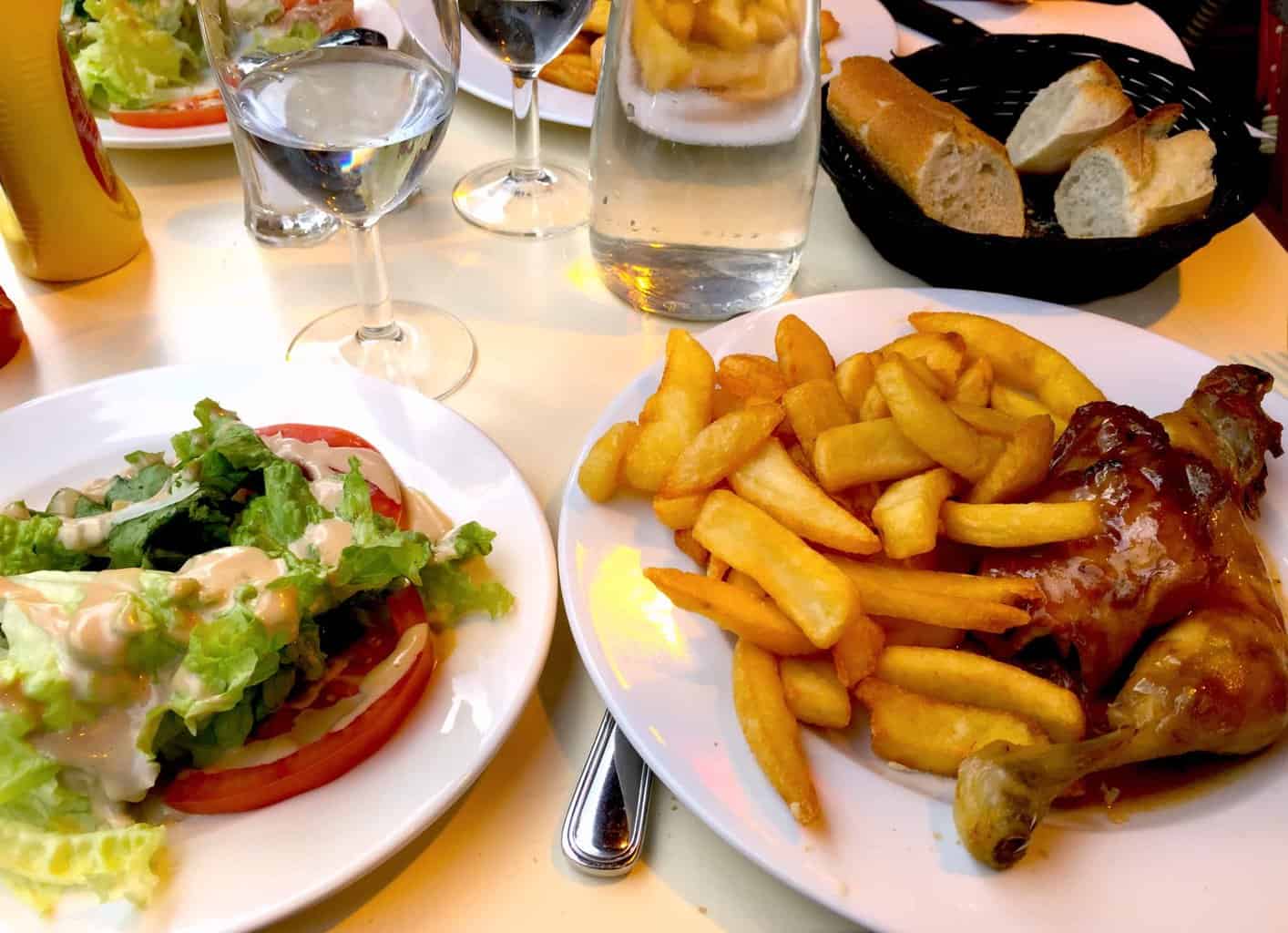 A plate of chicken and fries with a simple salad