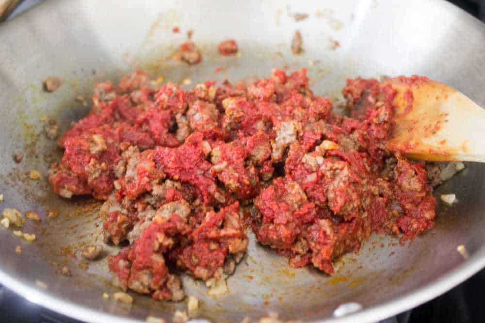 Simple Bolognese Recipe beef and tomato paste being sautéed in pan