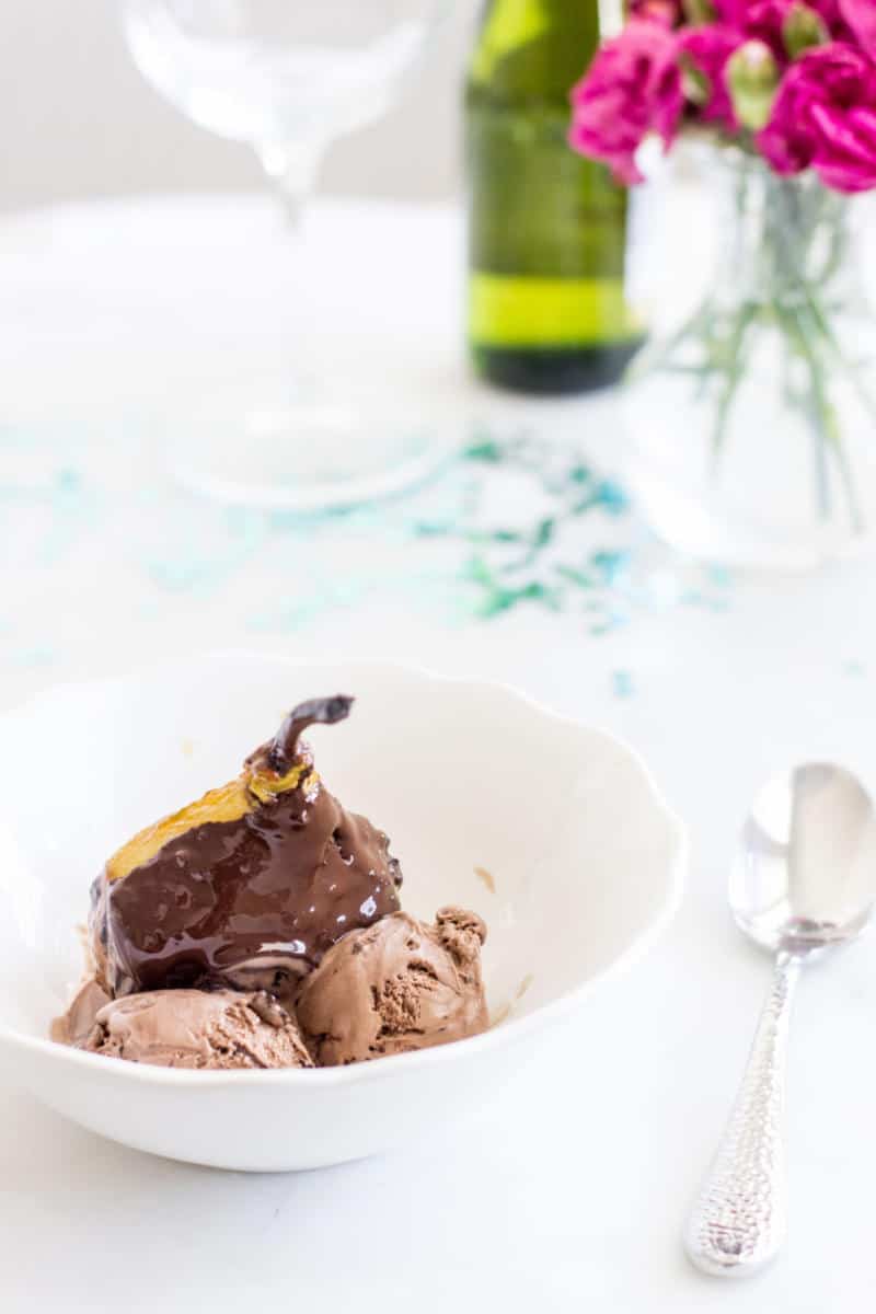 poached pears covered in chocolate sauce served with ice cream portrait view