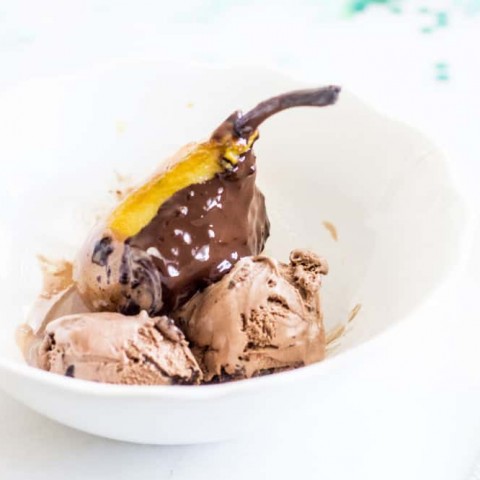 poached pear covered in chocolate sauce served with chocolate ice cream
