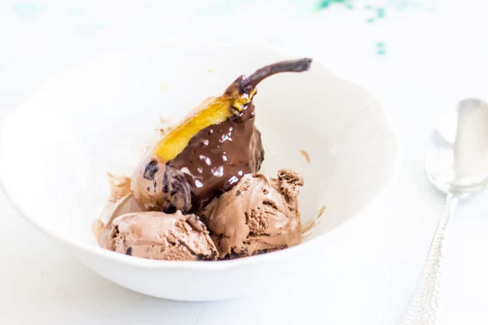 poached pear covered in chocolate sauce served with chocolate ice cream