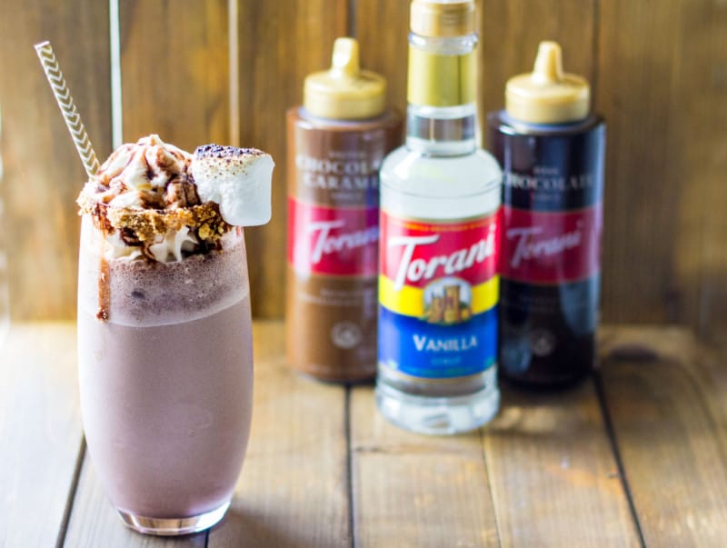 s'mores milkshake in a cup next to Torani syrups and sauces