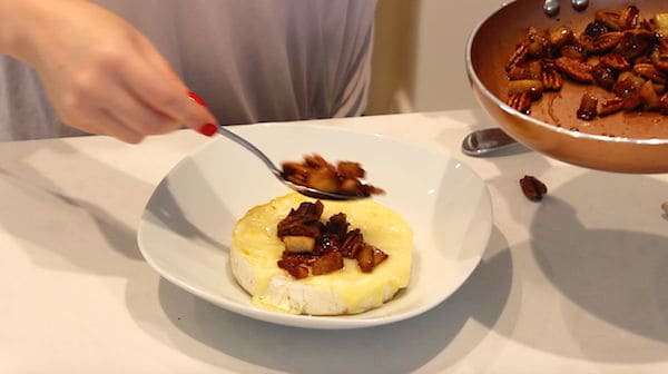 apple and pecans being scooped onto brie