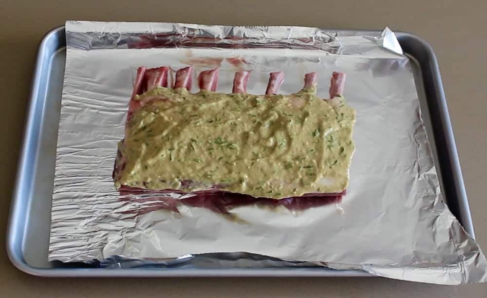 roast rack of lamb marinated on a baking sheet