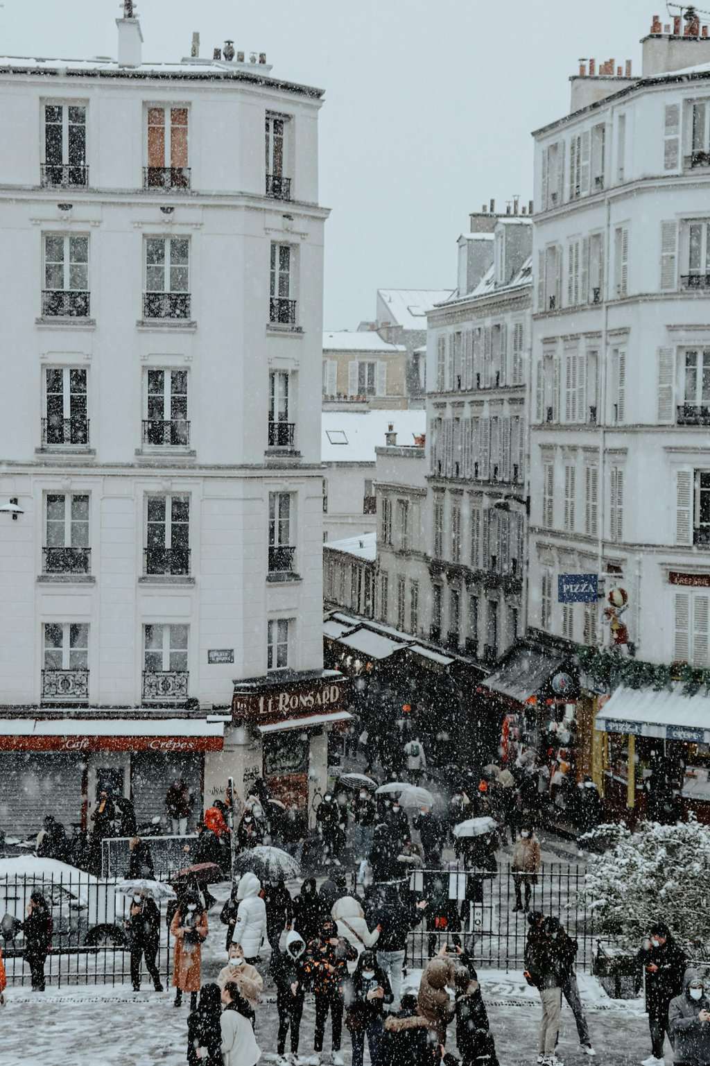 City street in Paris covered by snowfall with people gathering, creating a classic winter scene.
