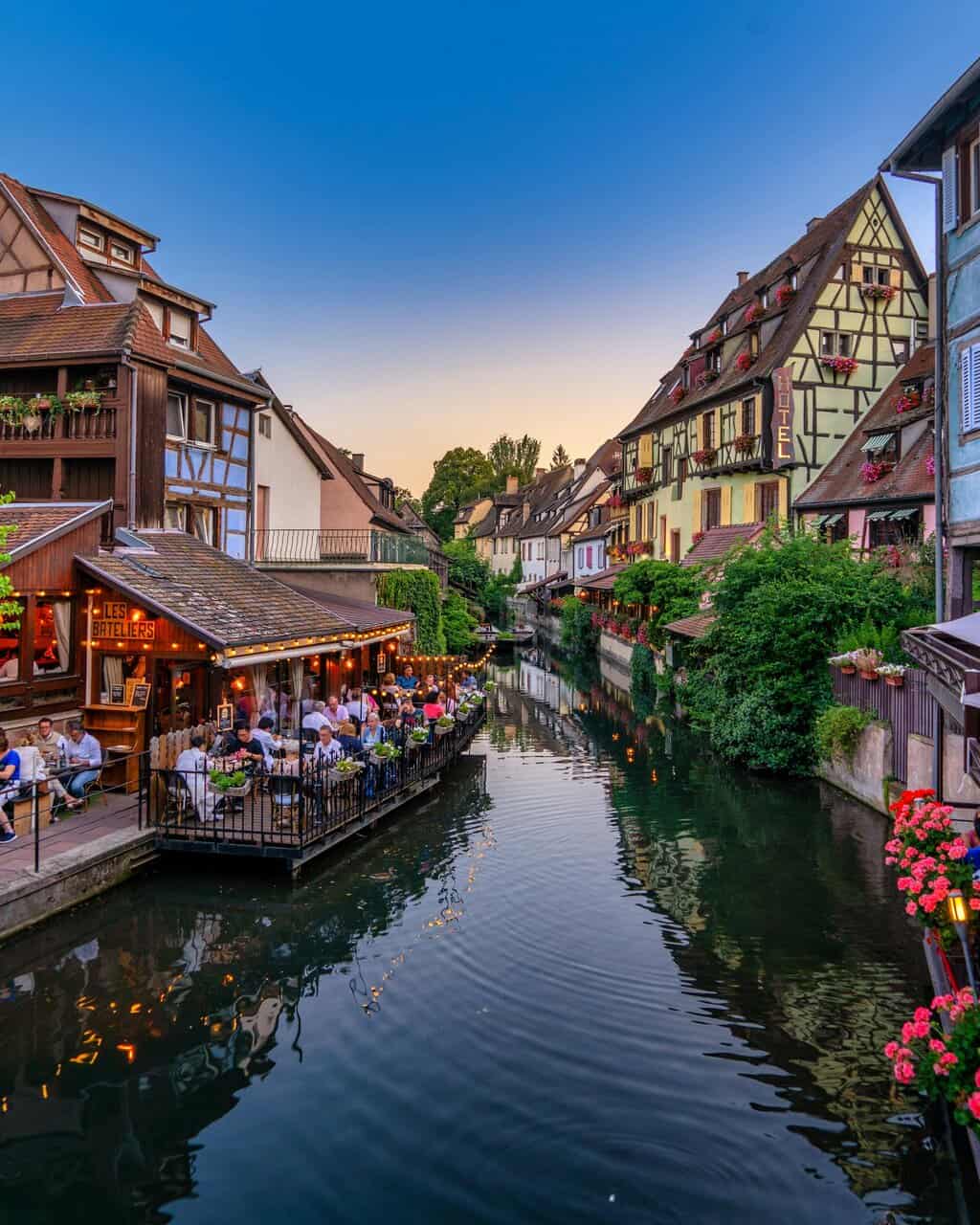 Scenic view of a picturesque canal with half-timbered houses in Colmar during sunset.