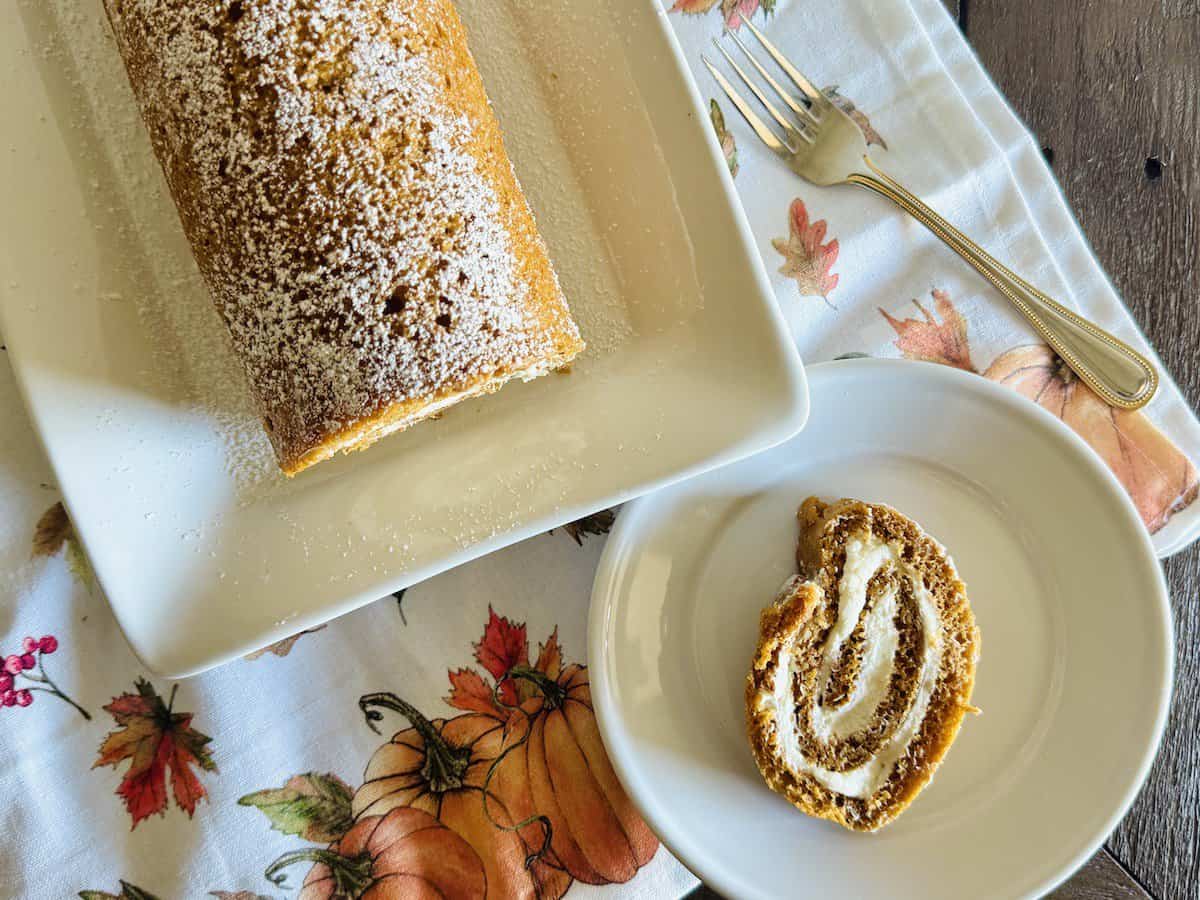 pumpkin roulade slice on a plate next to cake